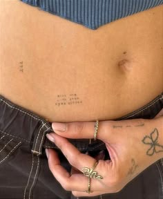 a woman's stomach with tattoos on it and her hand resting on the belly