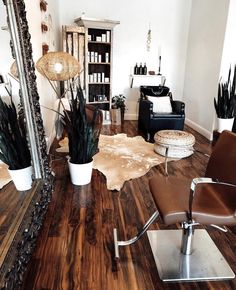 a chair and mirror in a room with wood flooring on the floor, plants are placed next to each other