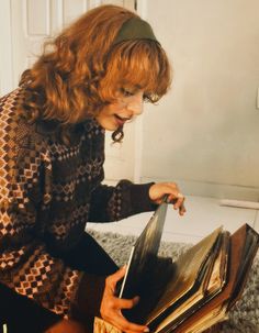 a woman sitting on the floor looking at an open book with a knife in it