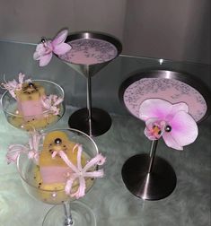 three desserts in glass dishes with pink flowers on the top and one is decorated like a bird