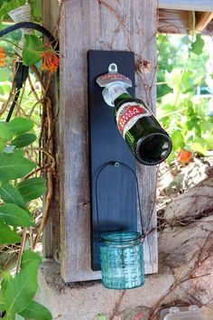 a beer bottle is hanging on a wooden post with a metal can attached to it