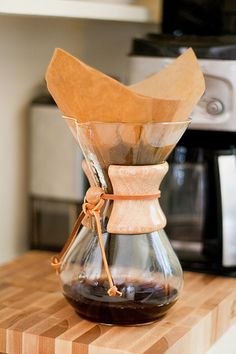 a coffee pot filled with liquid on top of a wooden cutting board