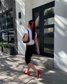 a woman walking down the street with a red bow in her hair