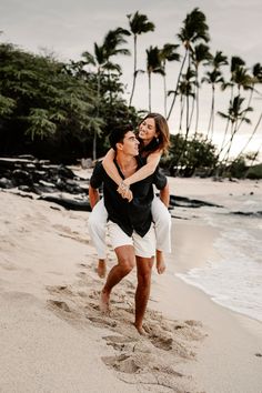 a man carrying a woman on his back at the beach with palm trees in the background