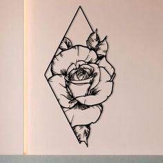 a drawing of a rose in a diamond shape on a white wall with black ink