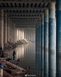 there are many pillars in the building that have water running through them and people standing on it