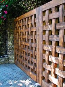 a wooden fence that is next to a brick walkway with flowers growing on the side