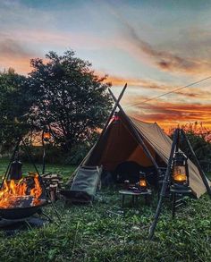 a tent is set up next to a campfire with candles in the foreground