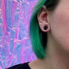 a woman with green hair and ear piercings