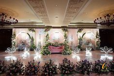 an elaborately decorated stage set up for a wedding ceremony with flowers and greenery