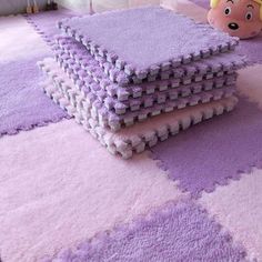 a pile of purple rugs sitting on top of a floor next to a stuffed animal