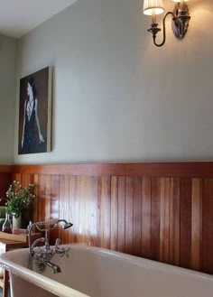 a bath tub sitting next to a wooden wall with two lights on it's side