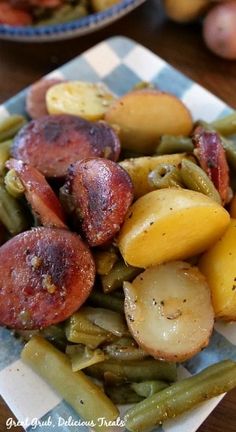 a plate full of green beans, potatoes and sausage on a checkered paper towel