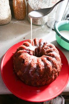 a bundt cake is being drizzled with icing on a red plate