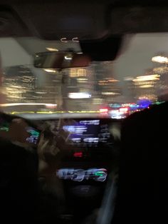 the inside of a car with city lights in the back ground and blurry background