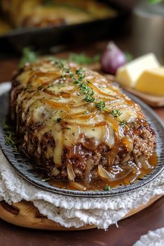 a meatloaf covered in gravy on a plate with onions and cheese