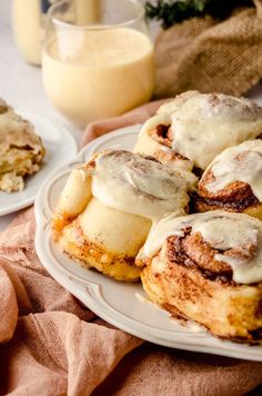 cinnamon rolls with icing on a plate next to a glass of milk and cookies