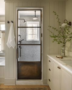 a bathroom with a glass door and white cabinets