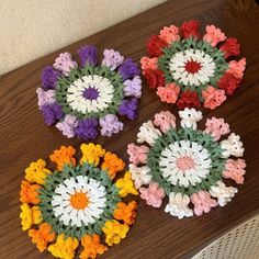 four crocheted coasters sitting on top of a wooden table