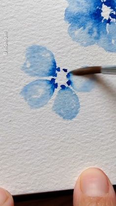 someone is using a paintbrush to paint a flower on a piece of white paper