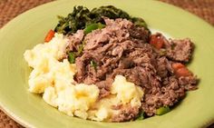 a green plate topped with meat and veggies on top of a brown table