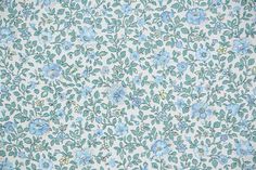 a blue and white flowered wallpaper with green leaves on the bottom right corner