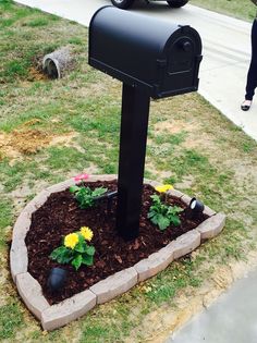 a mailbox sitting in the middle of a flower bed