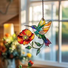 a stained glass hummingbird wind catcher hanging from a chain in front of a window