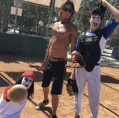 two young men with face paint on their faces are standing in the dirt while one man is holding a baseball mitt