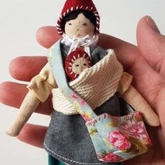 a hand holding a small doll with a red hat