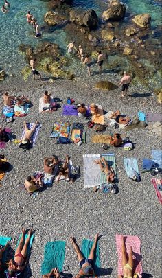 many people are laying on towels near the water