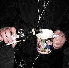 a man holding a wine glass and bottle in his hands with headphones attached to it