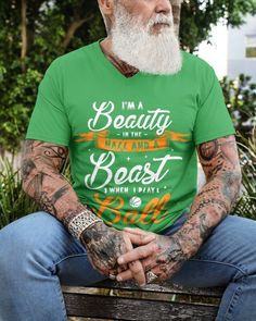 a man with tattoos sitting on a bench wearing a green t - shirt and jeans