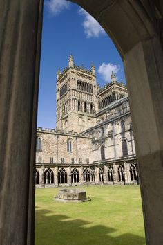 an old building with a large lawn in the foreground and blue sky behind it