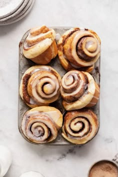 cinnamon buns on a baking sheet with coffee in the background