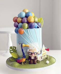 a birthday cake with balloons on top and a man holding a bird figurine