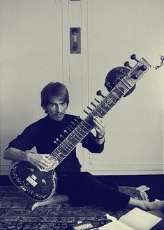 a man sitting on the floor holding an instrument