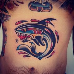 a man's chest with tattoos on it and an image of a shark in the middle