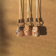 four small ceramic animals hanging from hooks on a brown cloth covered floor with white cords