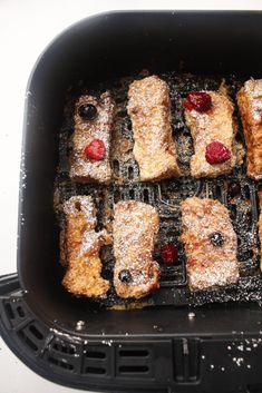 several pastries are being cooked on a grill with powdered sugar and raspberries