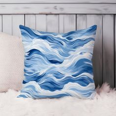 a blue and white pillow sitting on top of a fur covered bed next to pillows