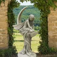 a statue of a woman sitting on top of a moon in front of an arch