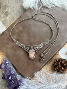 a necklace and earring set on a table next to some feathers, pine cones and other items