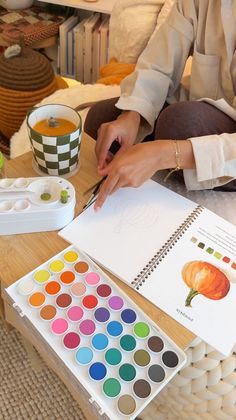 a woman sitting at a table with paint and watercolors