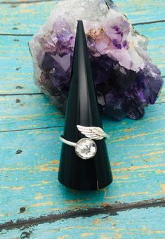 a ring sitting on top of a black cone next to a rock and purple crystals