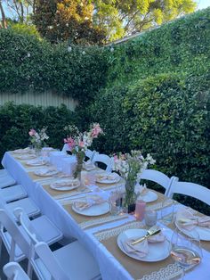 a long table set up with plates and place settings for an outdoor dinner party in the backyard