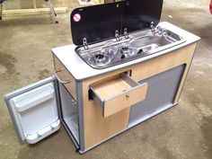 an outdoor kitchen with a sink and icebox attached to the outside wall that is open