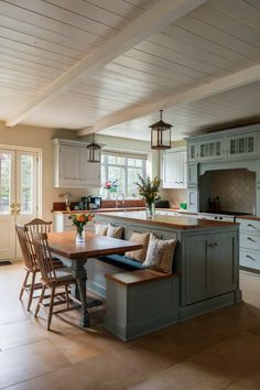 a kitchen filled with lots of counter space and wooden chairs next to a center island