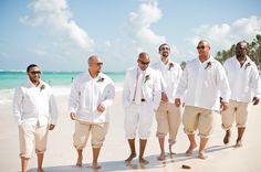 a group of men standing on top of a sandy beach