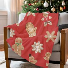 a red blanket with gingerbreads and snowflakes on it sitting in front of a christmas tree